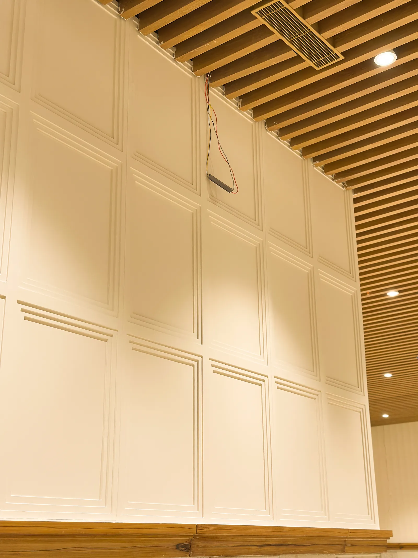 Panelled wall beneath a timber-slat ceiling — Chalukya Samrat